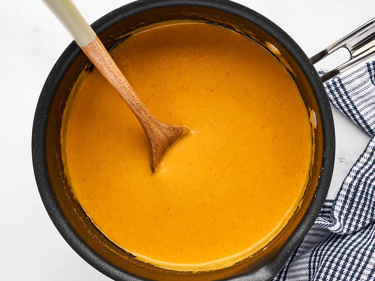 overhead view of thick and creamy beer cheese dip in saucepan with wooden spoon