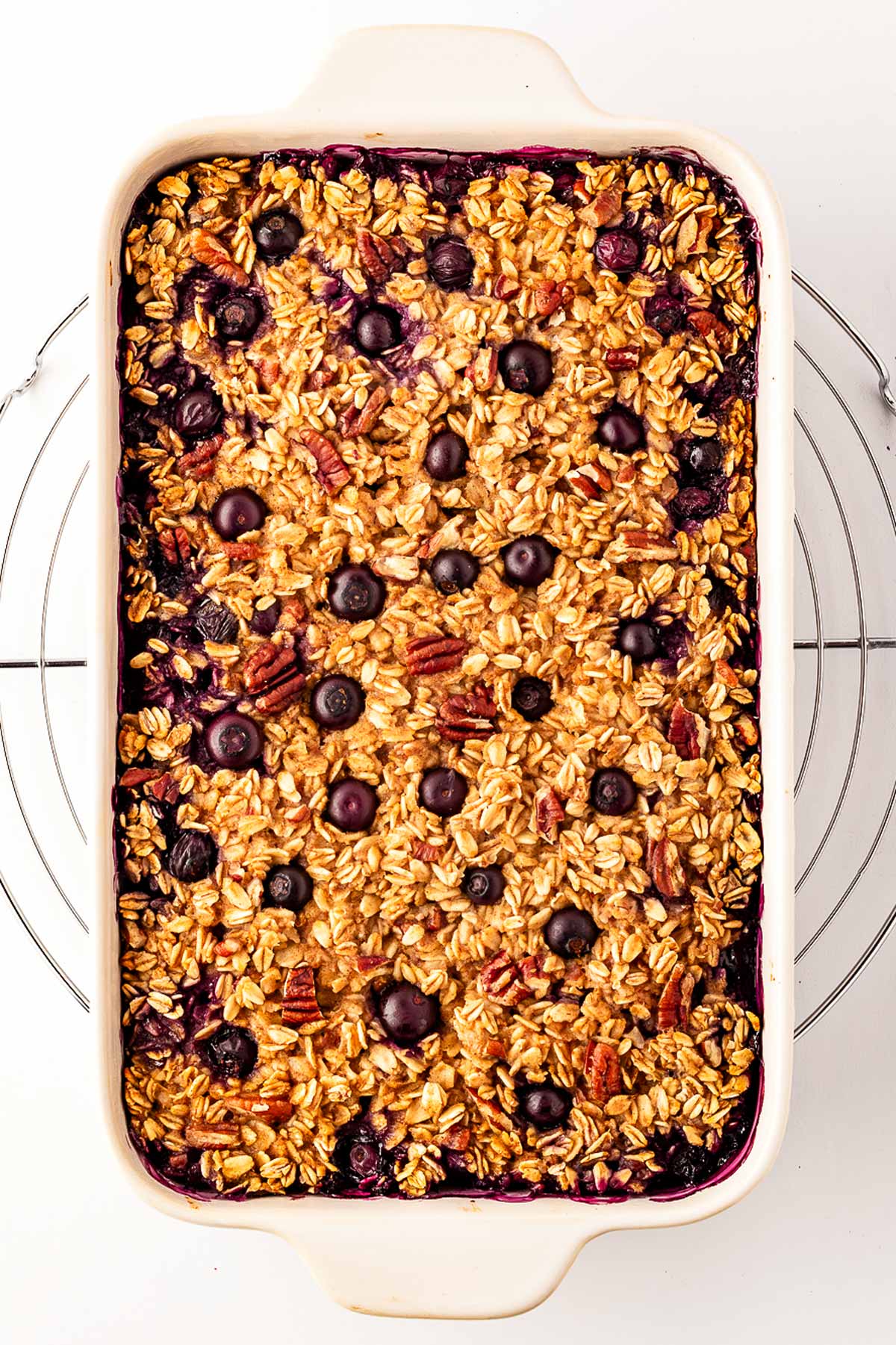 overhead view of blueberry baked oatmeal in white baking dish on top of wire rack