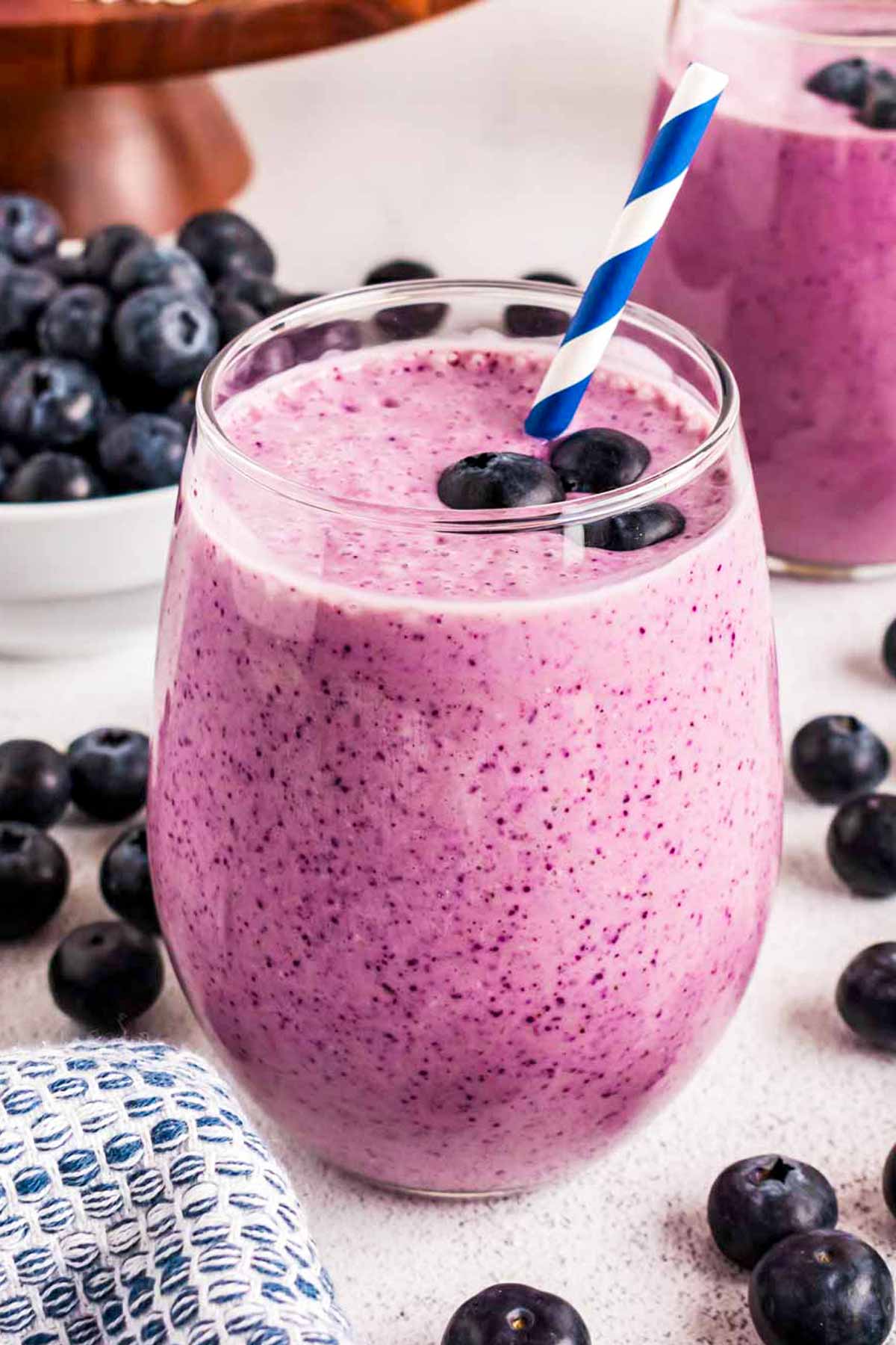 frontal view of blueberry banana smoothie in glass with straw