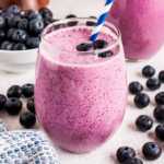 frontal view of blueberry banana smoothie in glass with straw