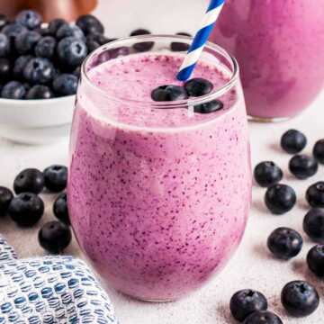 frontal view of blueberry banana smoothie in glass with straw