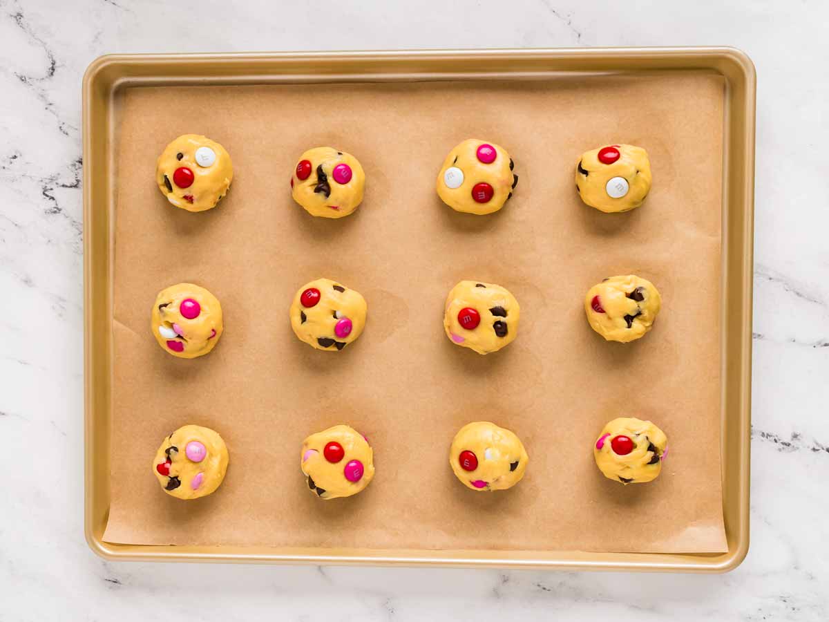 overhead view of cookie dough balls on lined baking sheet