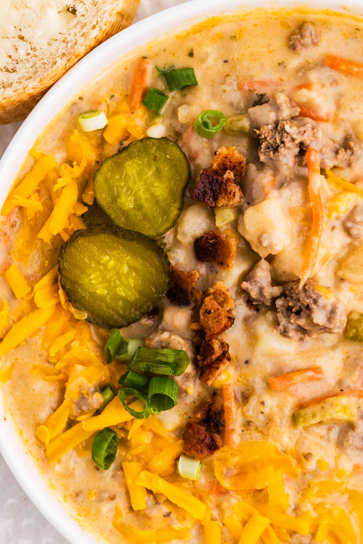 overhead close up view of cheeseburger soup garnished with pickles