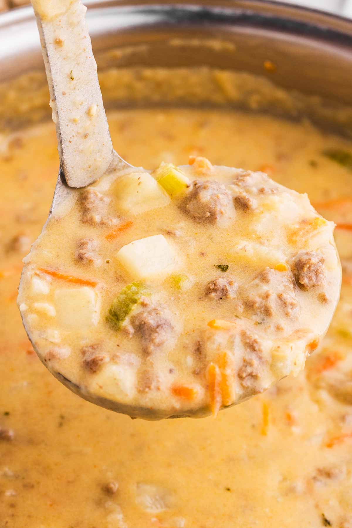 frontal view of ladle filled with cheeseburger soup