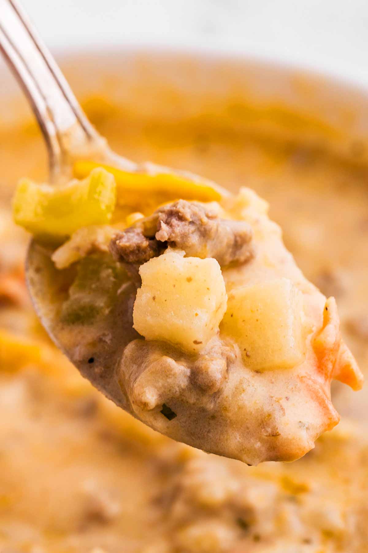 frontal view of cheeseburger soup on a spoon