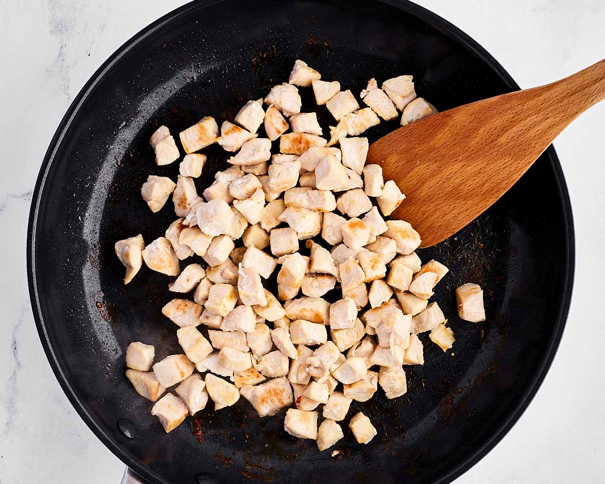 overhead view of cooked diced chicken in skillet