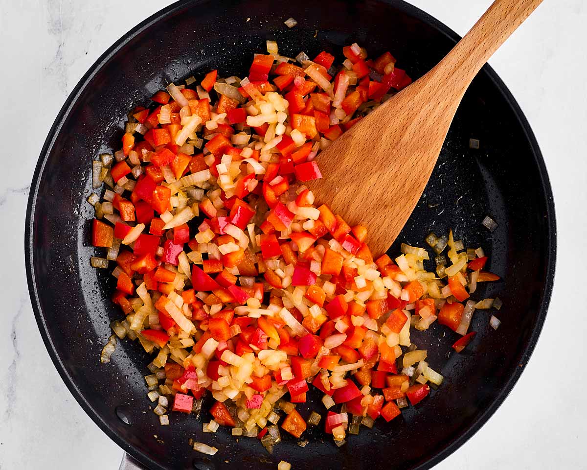 overhead view of cooked onion and red pepper in skillet