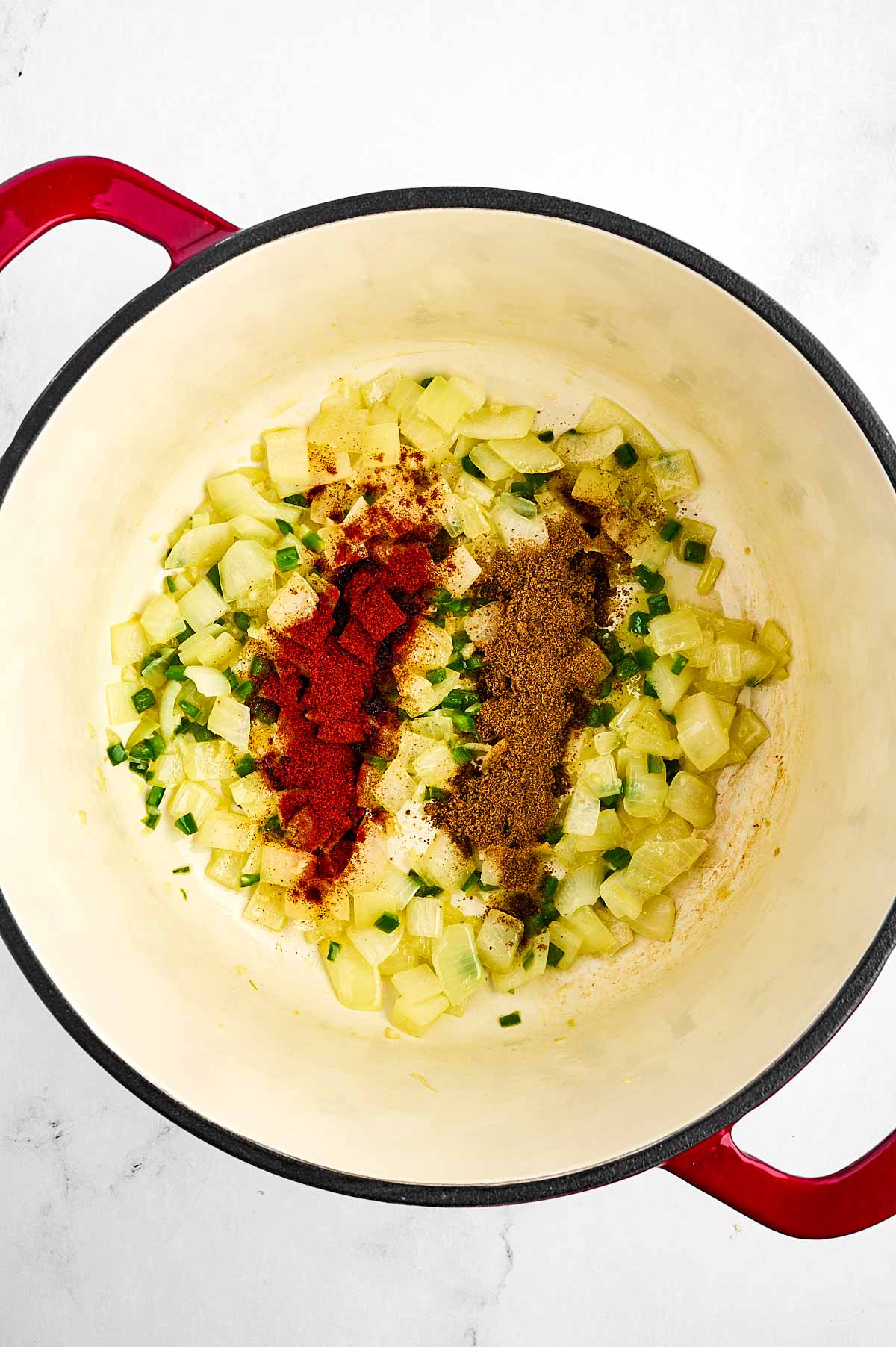 overhead view of cooked aromatics in pot with spices