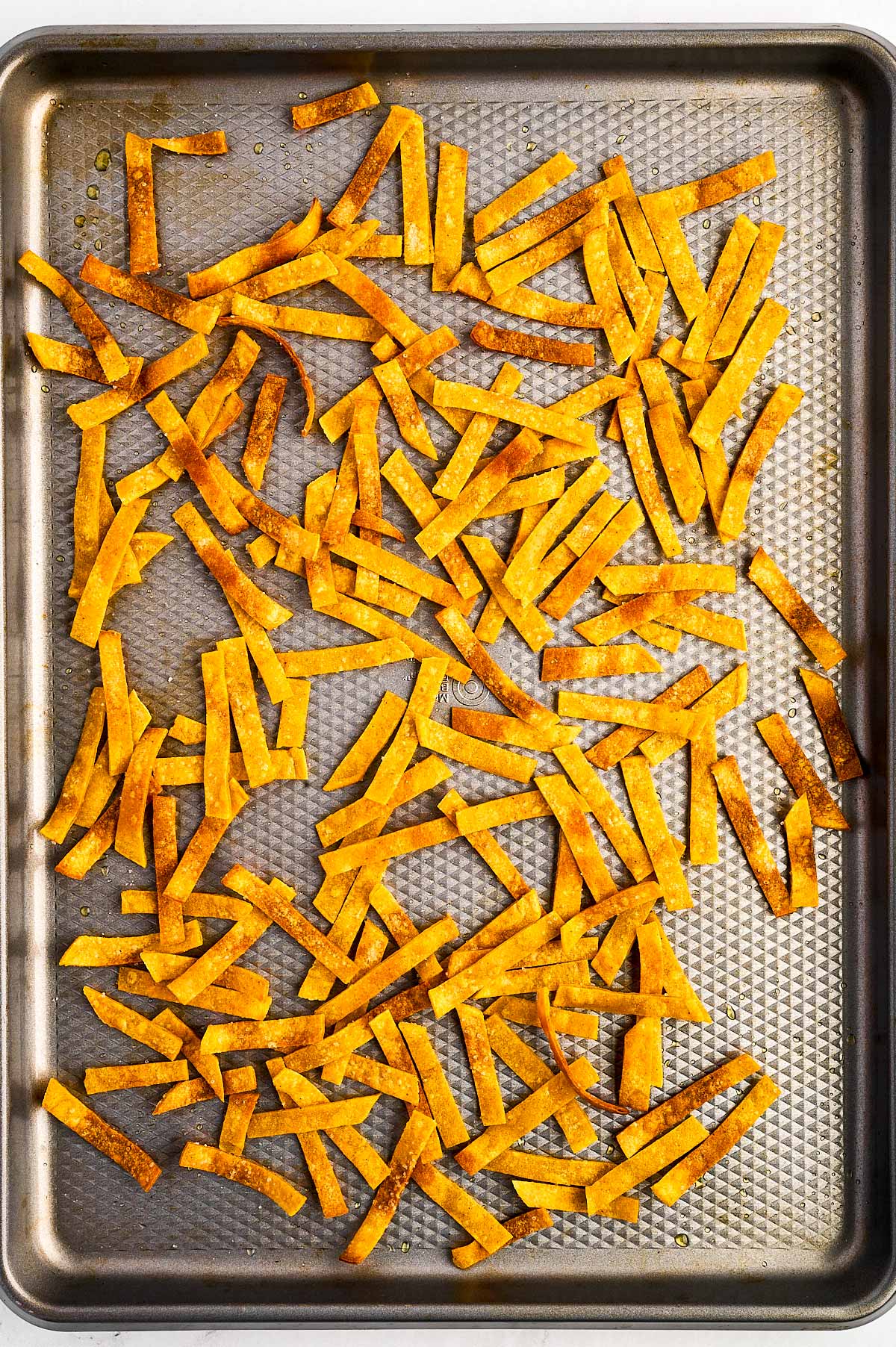 overhead view of baked tortilla strips on baking sheet