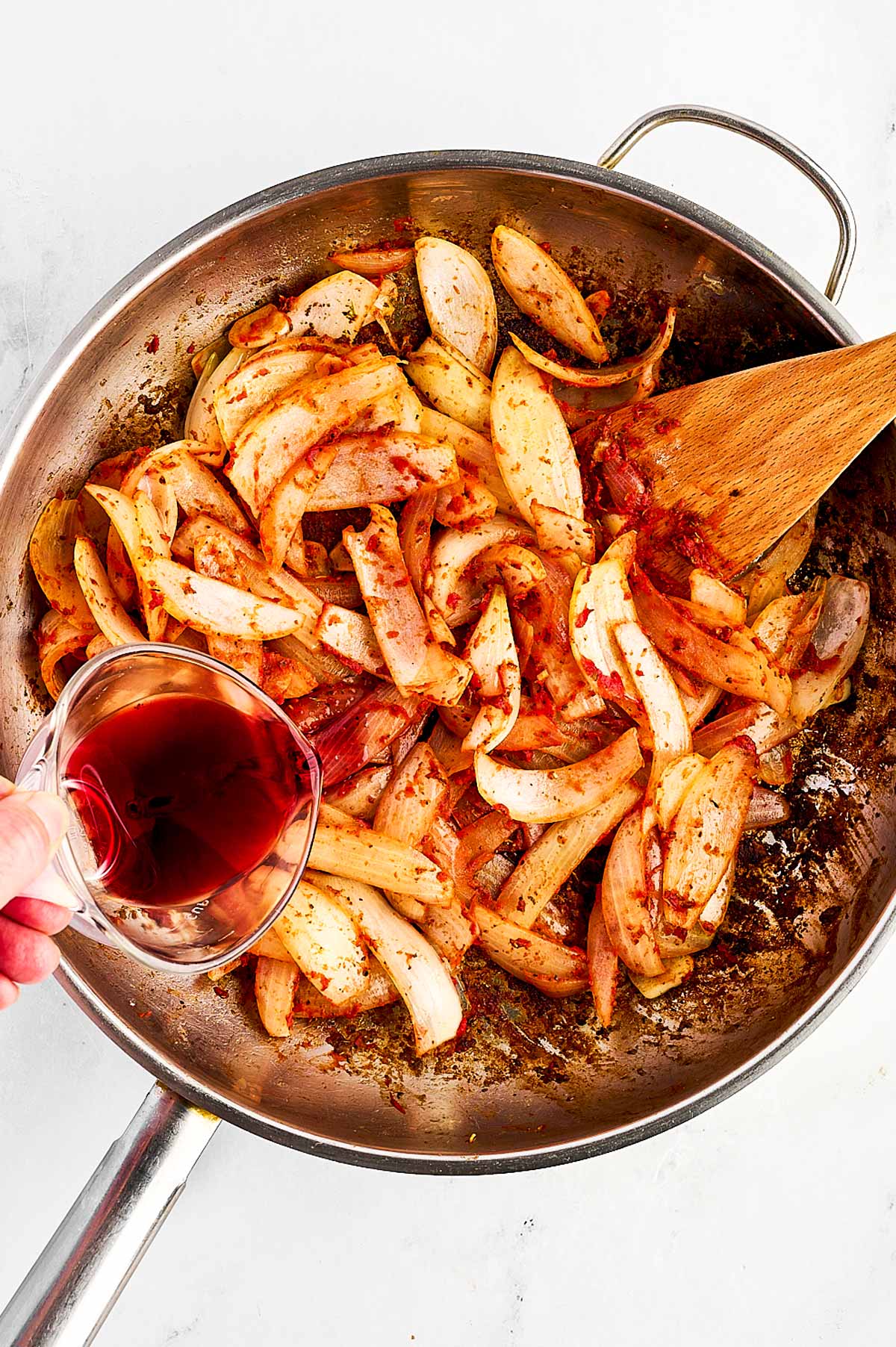 overhead view of wine poured into skillet with onion and tomato paste