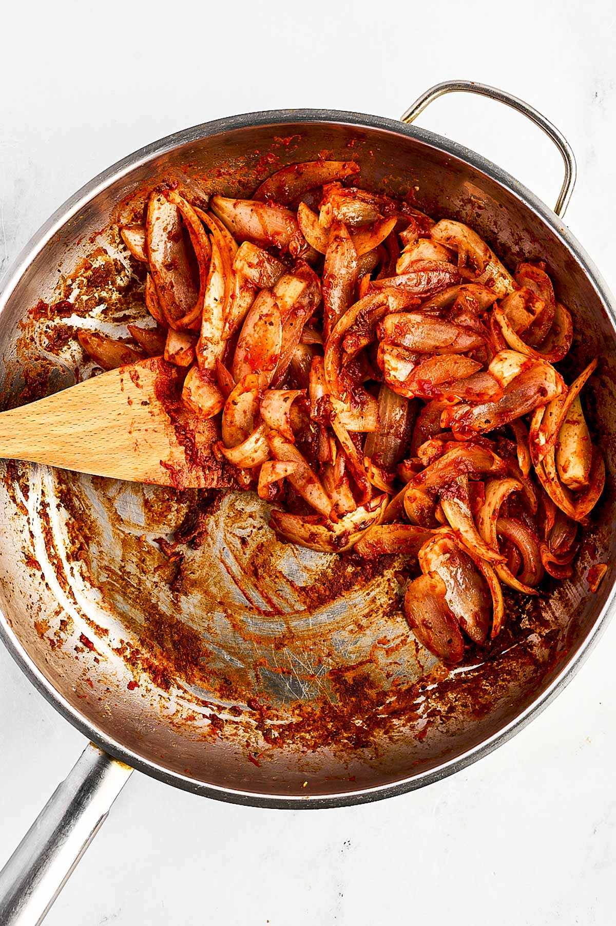 overhead view of red wine, onion and tomato paste cooked in skillet