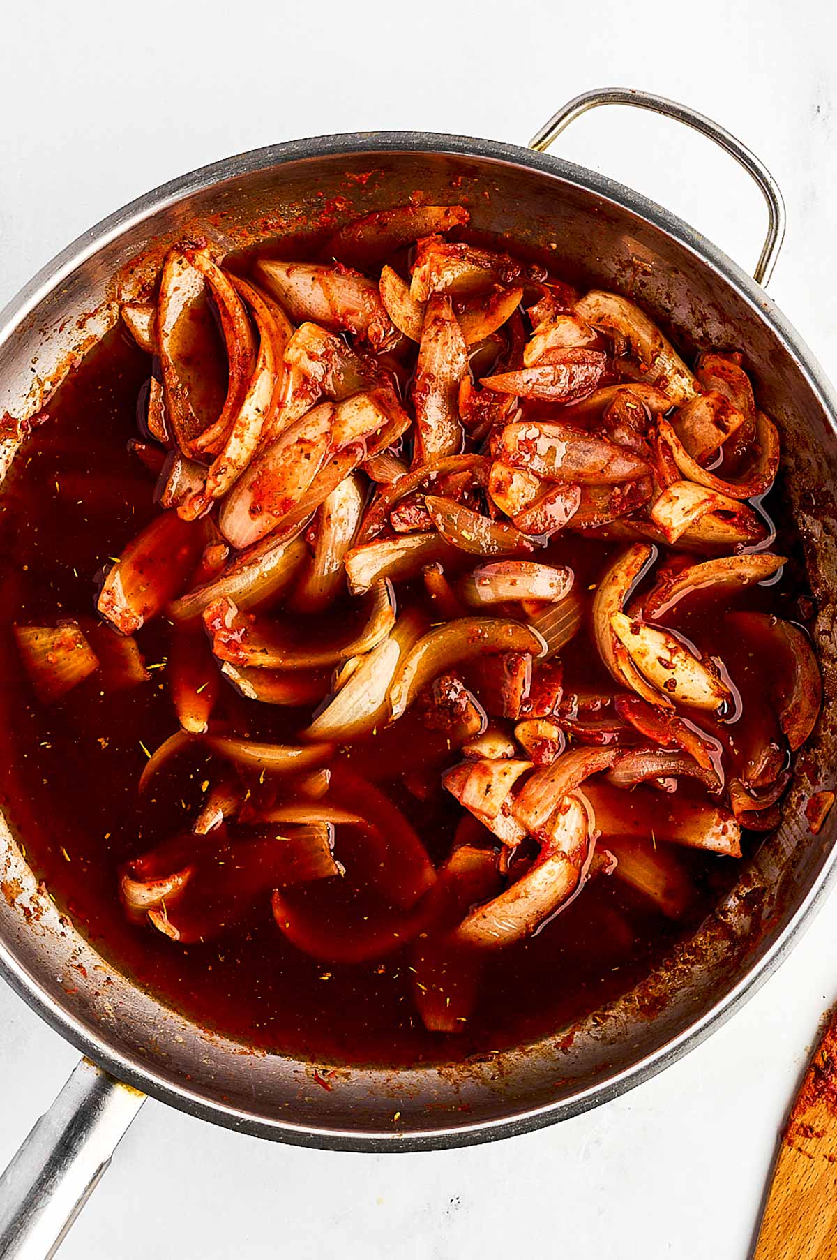 overhead view of red wine, onion and tomato paste cooked in skillet with beef broth