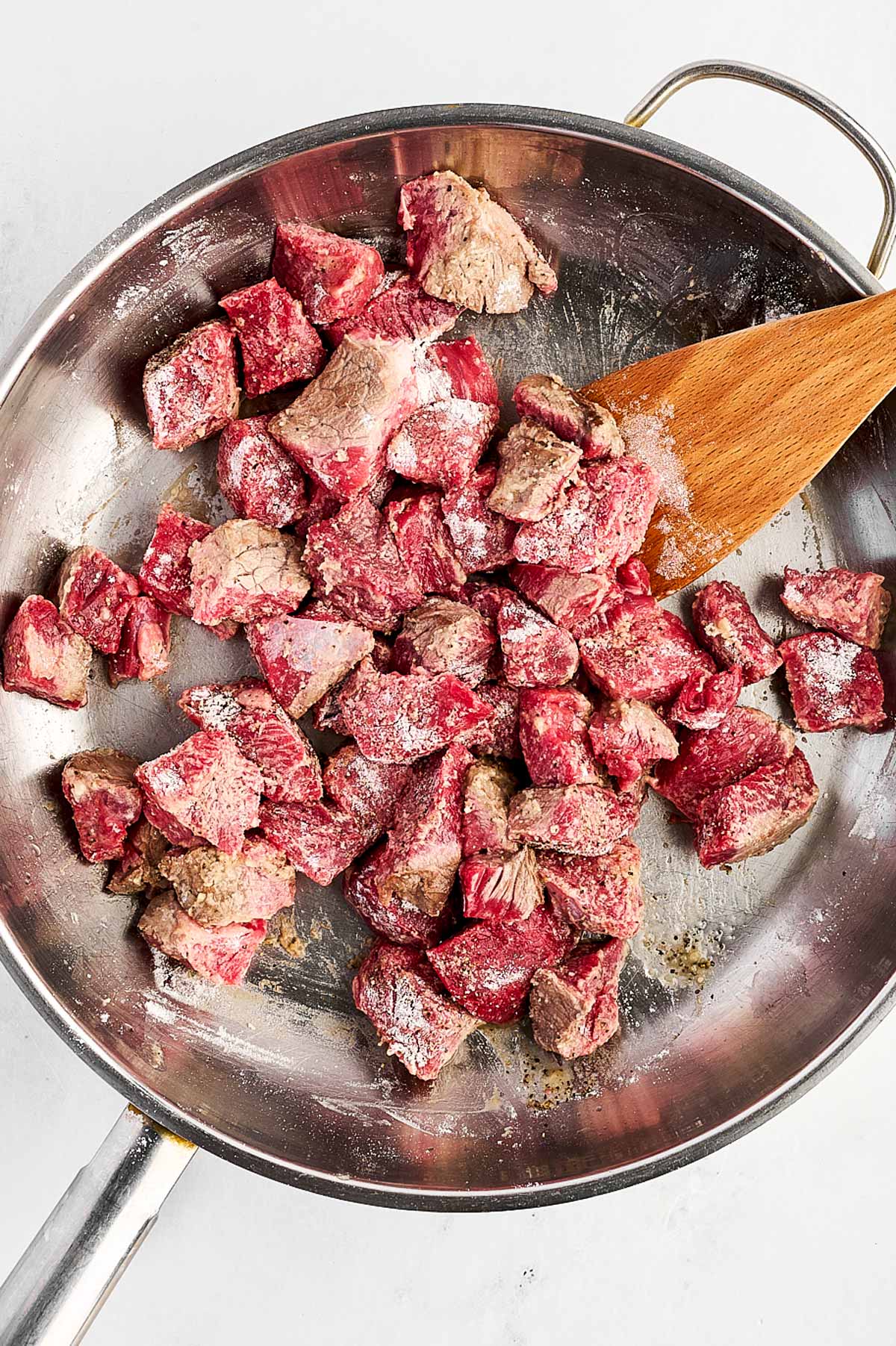 overhead view of floured beef in skillet