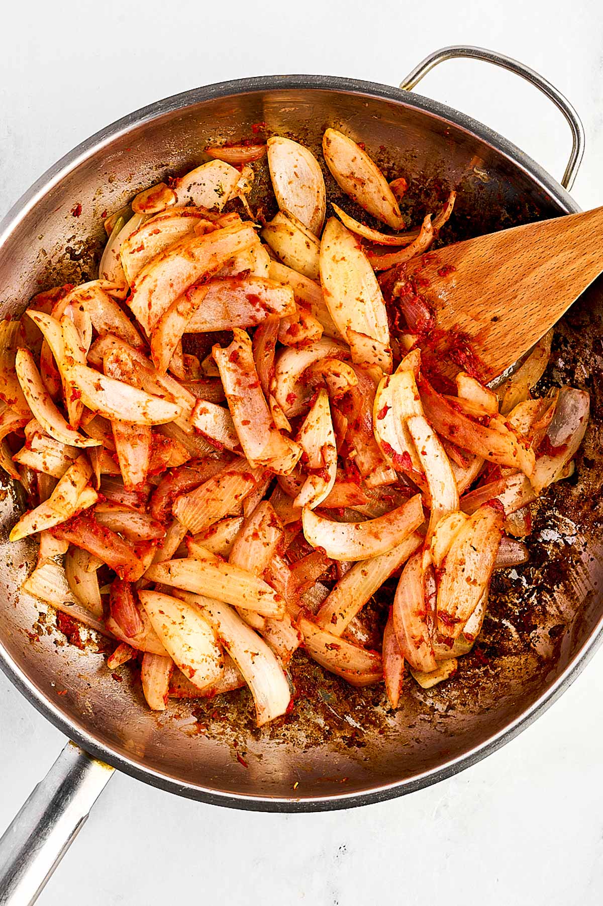 overhead view of onion and tomato paste in skillet