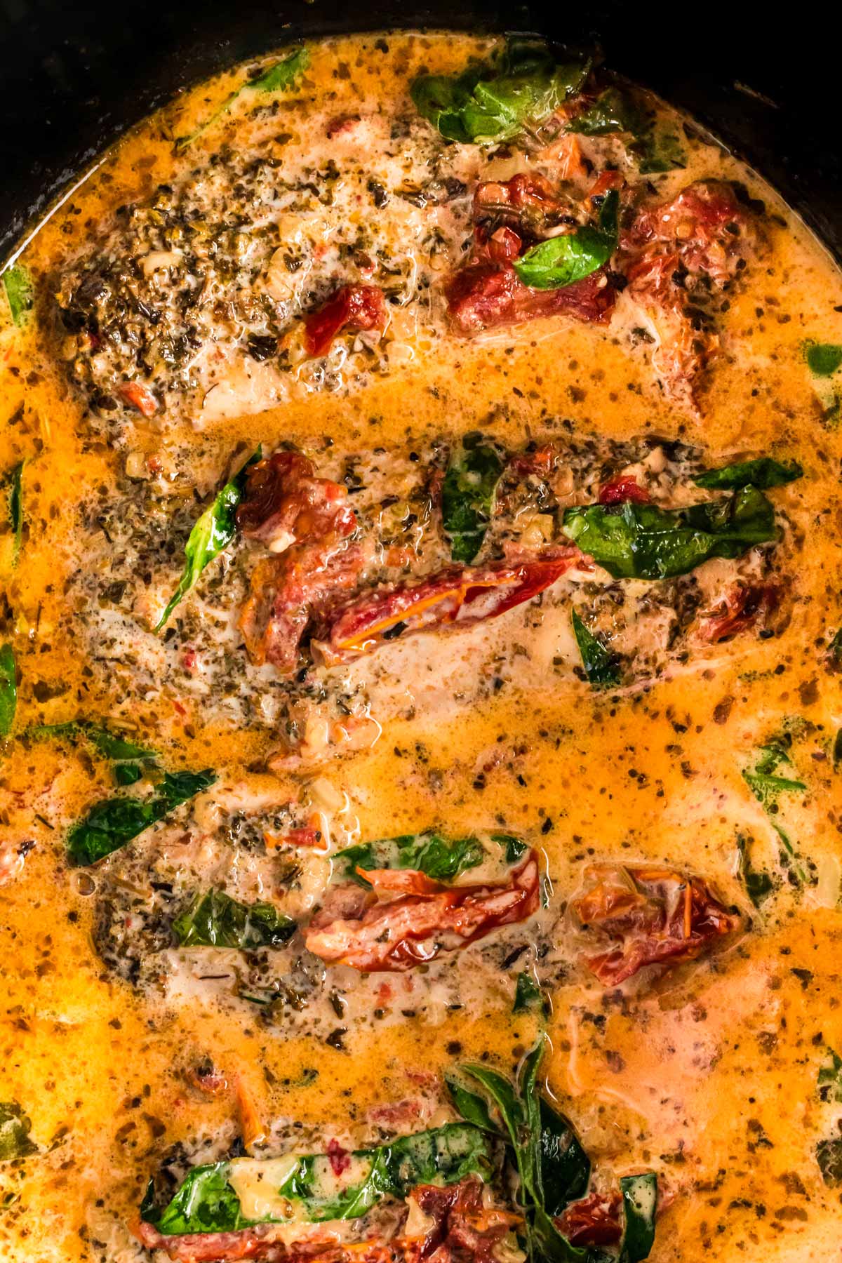 overhead view of tuscan chicken breast in black crockpot