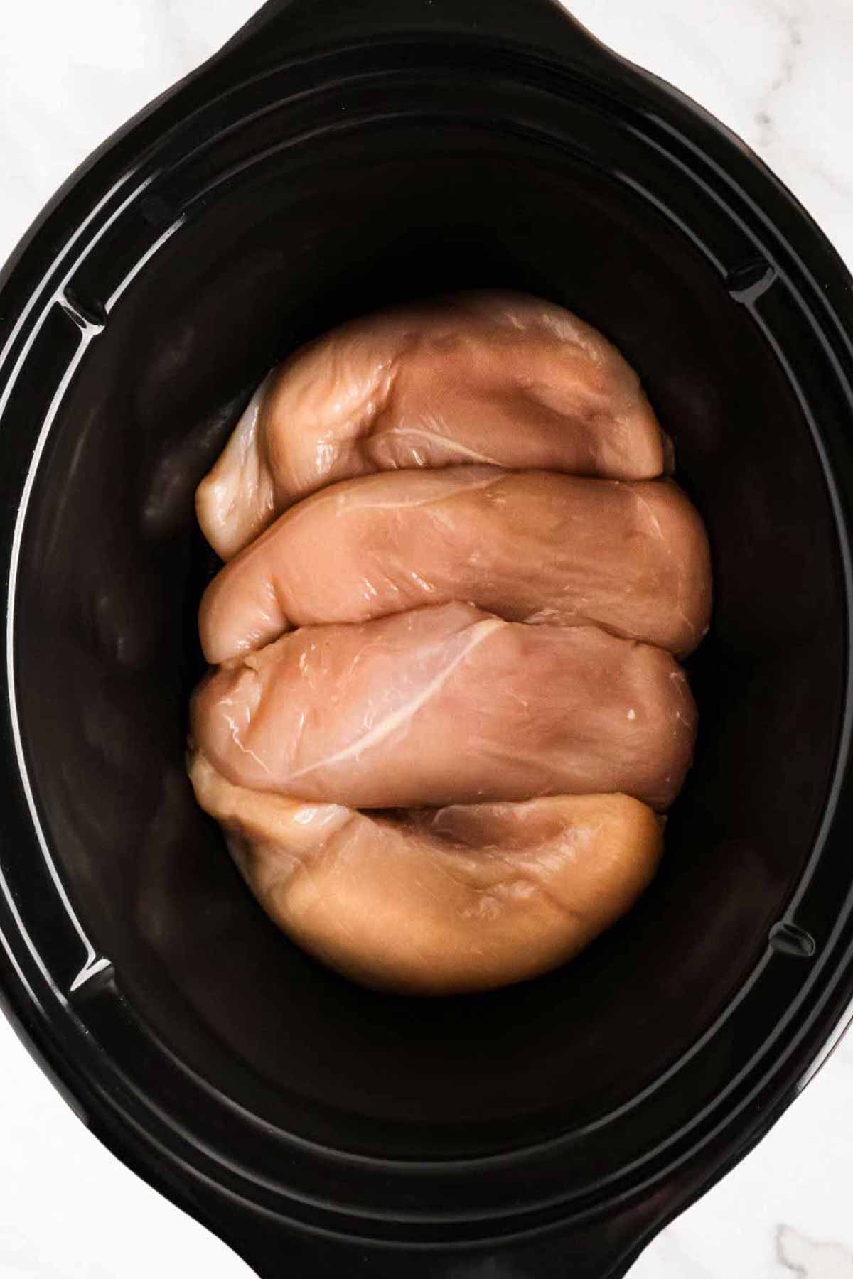 overhead view of chicken breasts in slow cooker