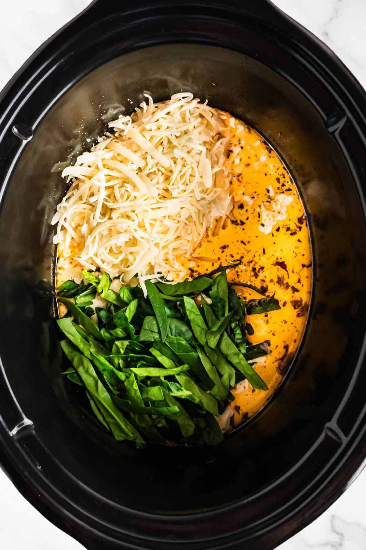 overhead view of spinach and cheese in slow cooker