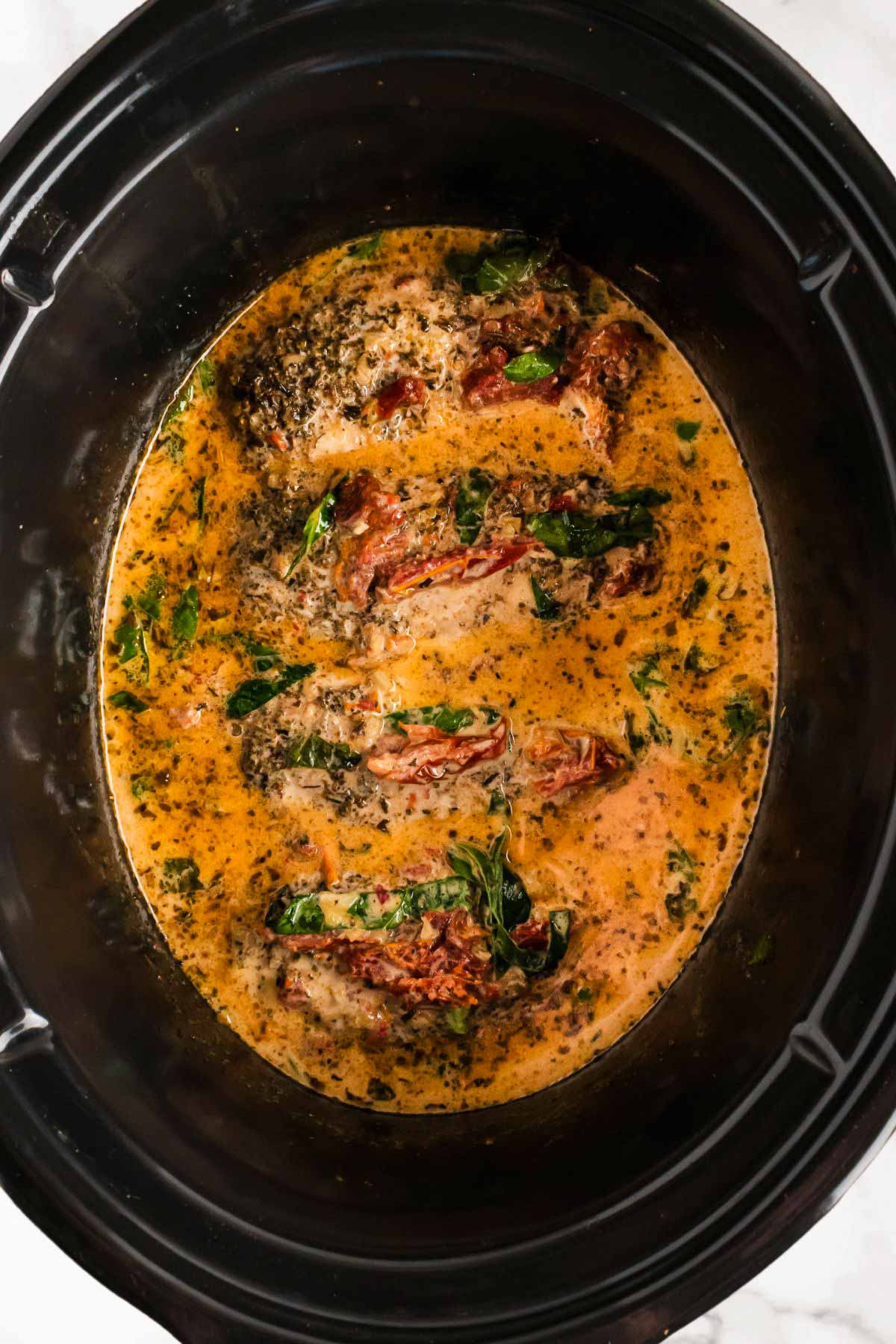 overhead view of tuscan chicken in slow cooker