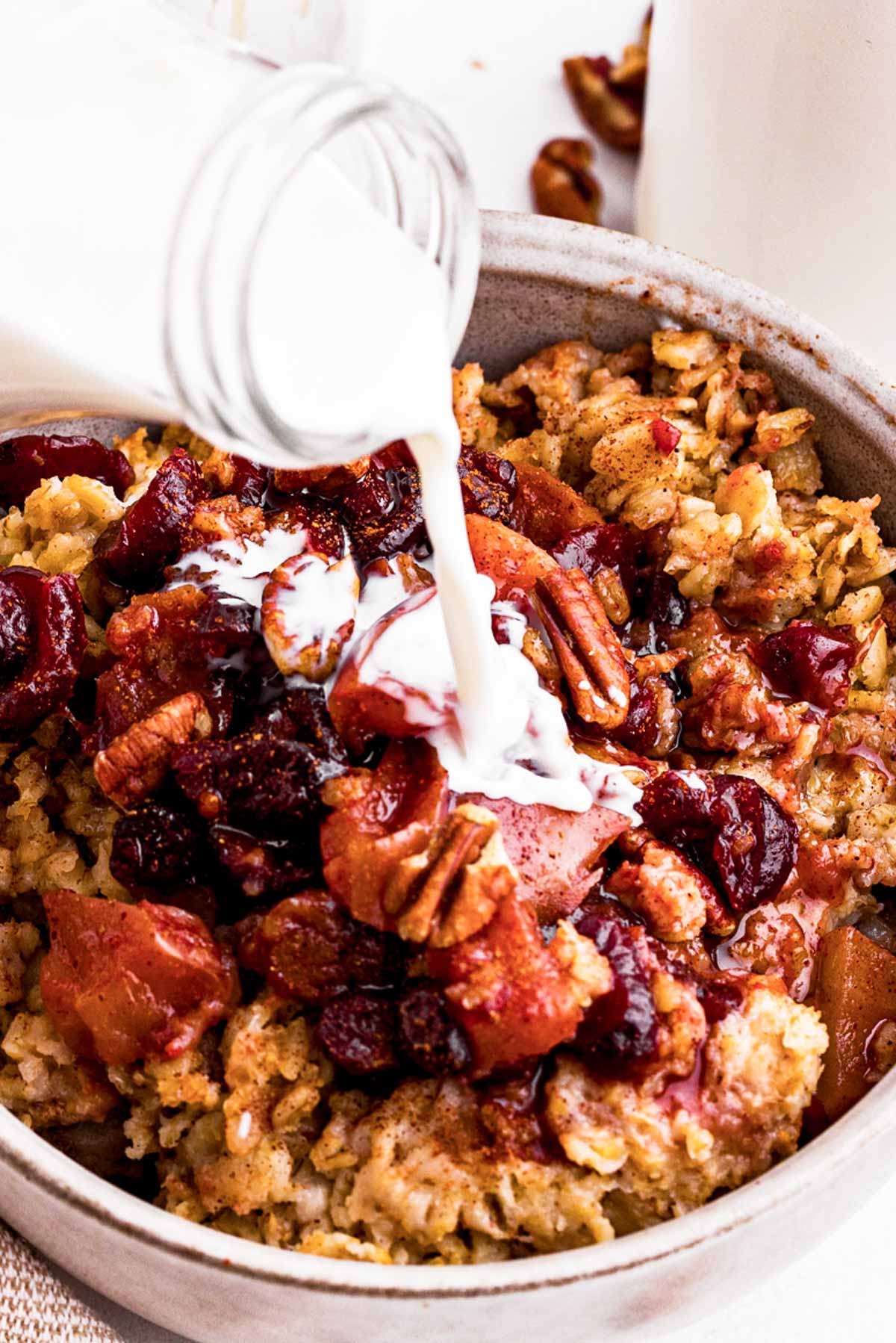 frontal view of milk pouring over apple oatmeal in bowl