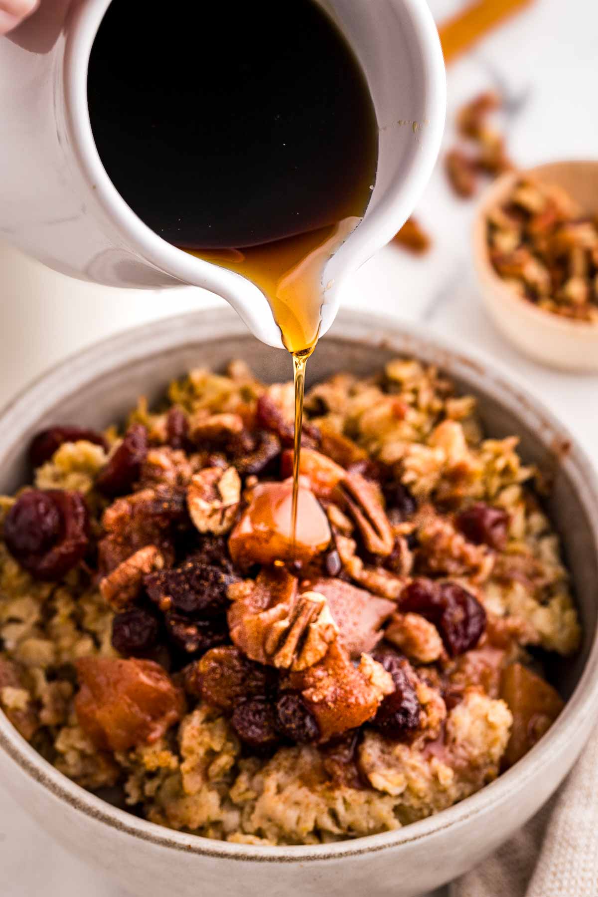 frontal view of maple syrup drizzling over oatmeal in bowl