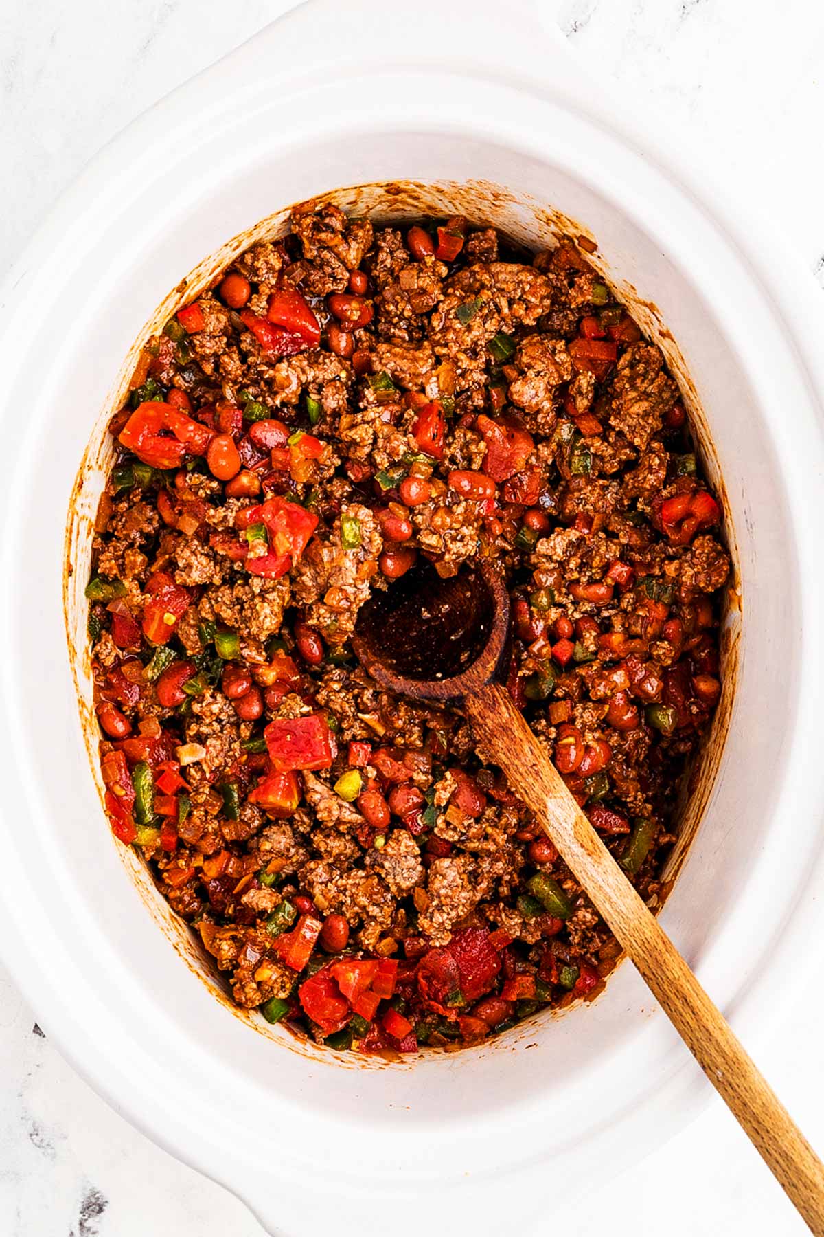 overhead view of uncooked ground beef chili in slow cooker