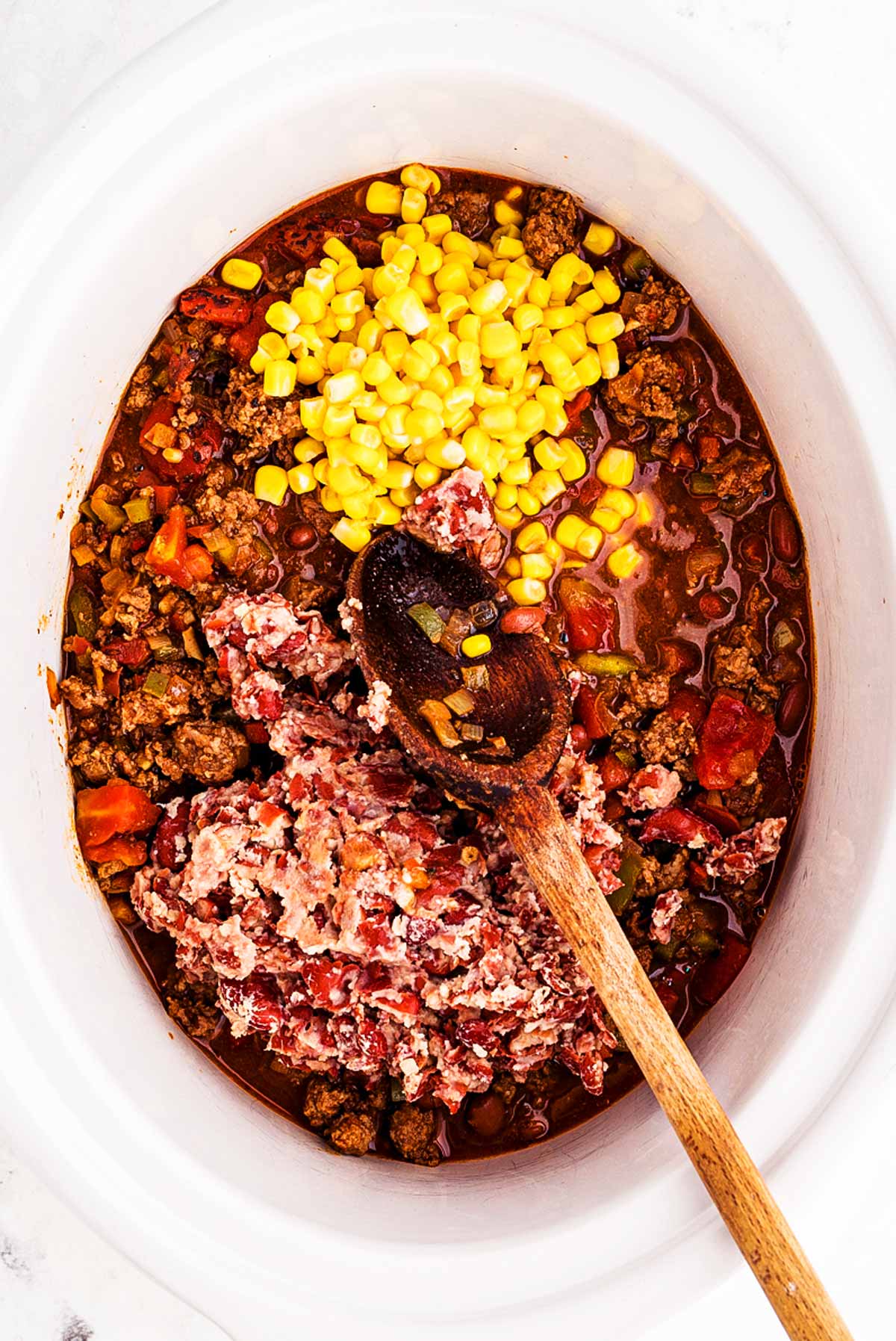 overhead view of mashed kidney beans on top of chili in slow cooker