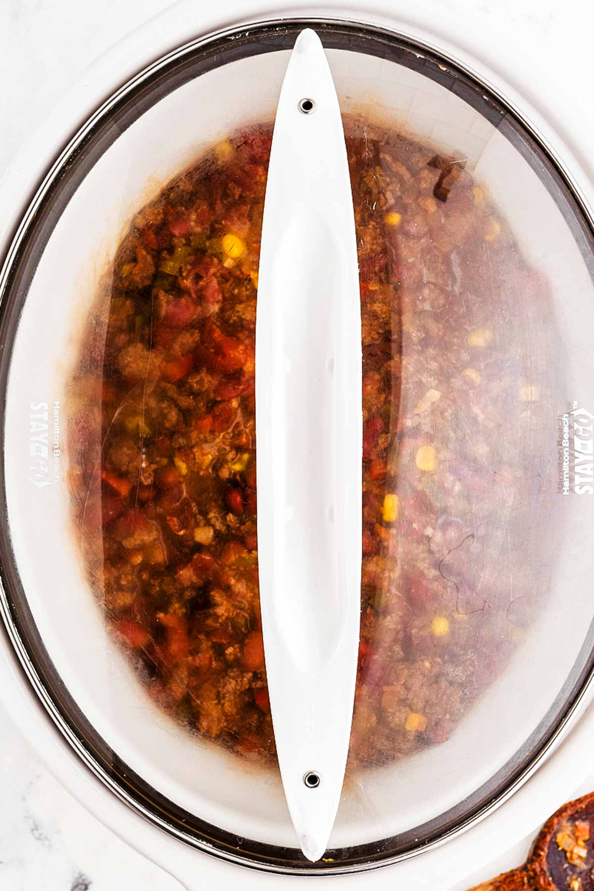 overhead view of stirred chili in slow cooker with lid on