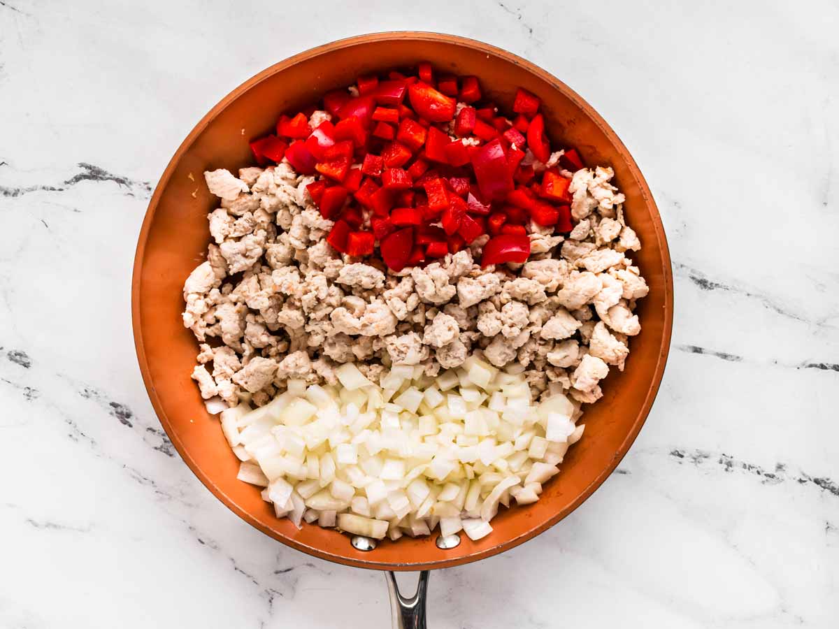 overhead view of cooked ground turkey, diced red pepper and onion in skillet