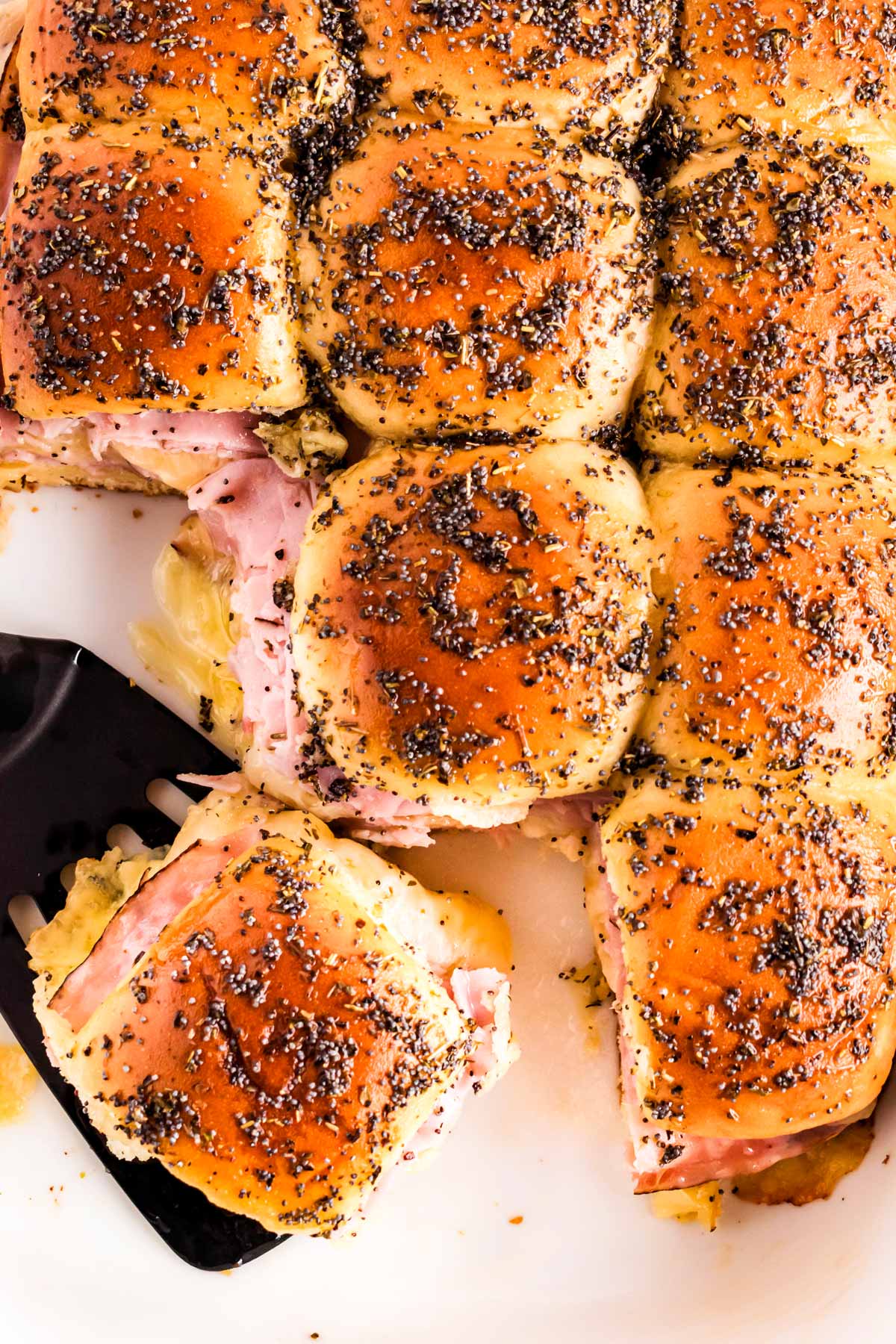 overhead view of hot ham sliders separated with spatula