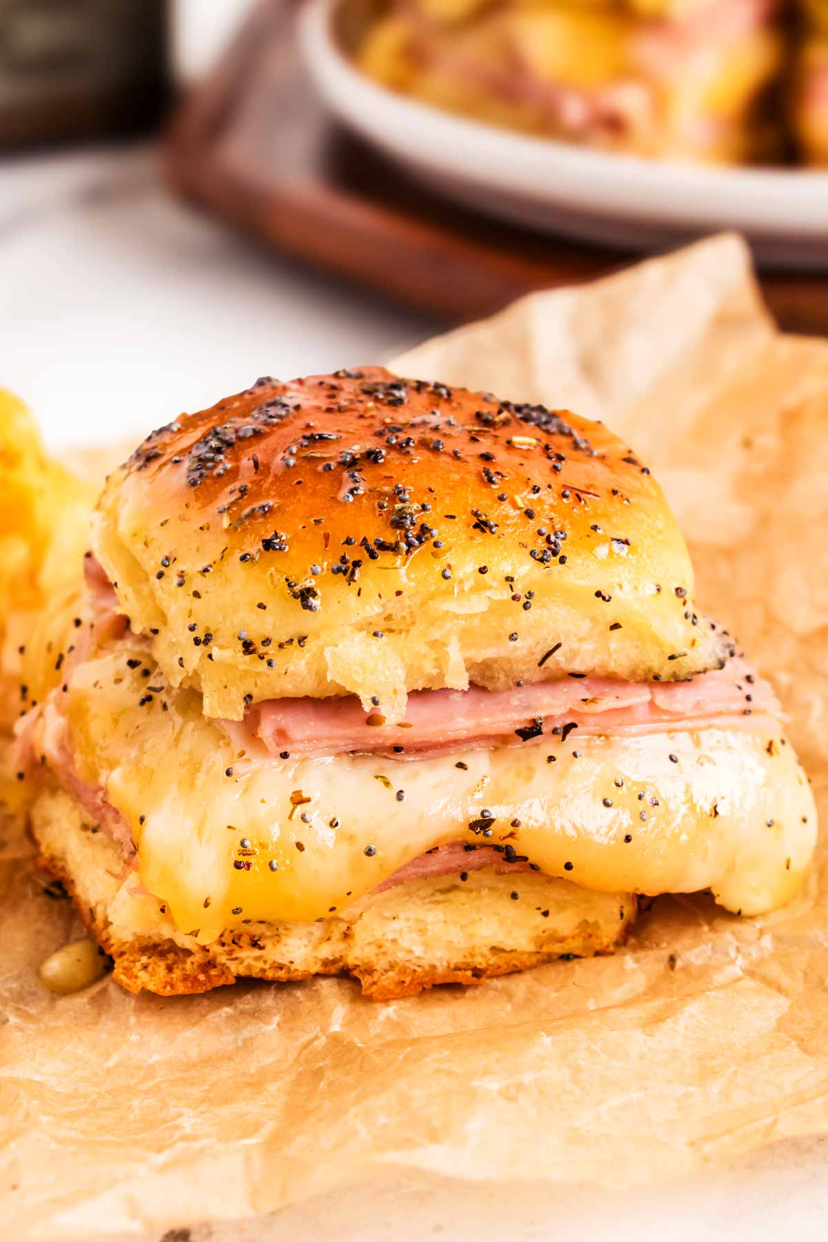 frontal view of hot garlic herb ham slider on parchment paper