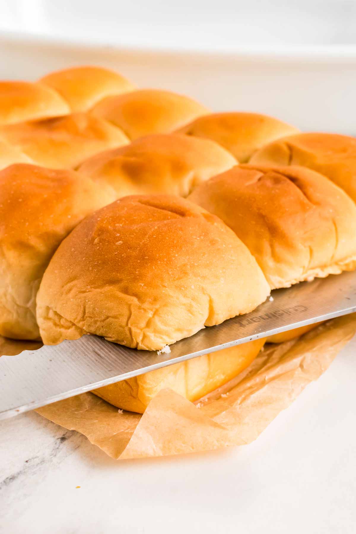 frontal view of slab of dinner rolls being sliced