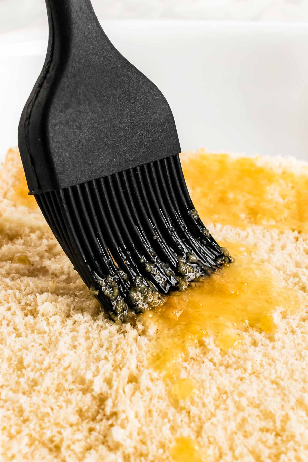 frontal view of silicone brush dabbing butter on sliced rolls