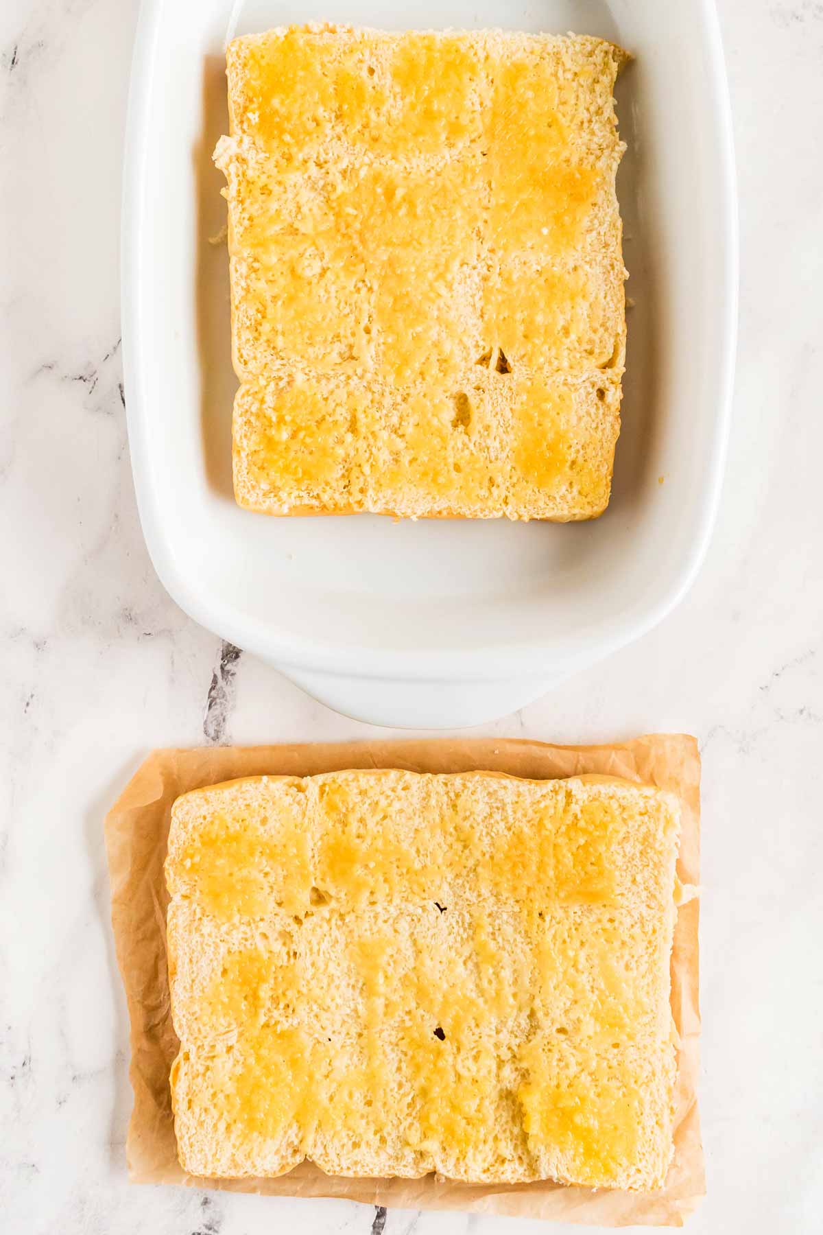 overhead view of halved dinner roll slab dabbed with melted butter