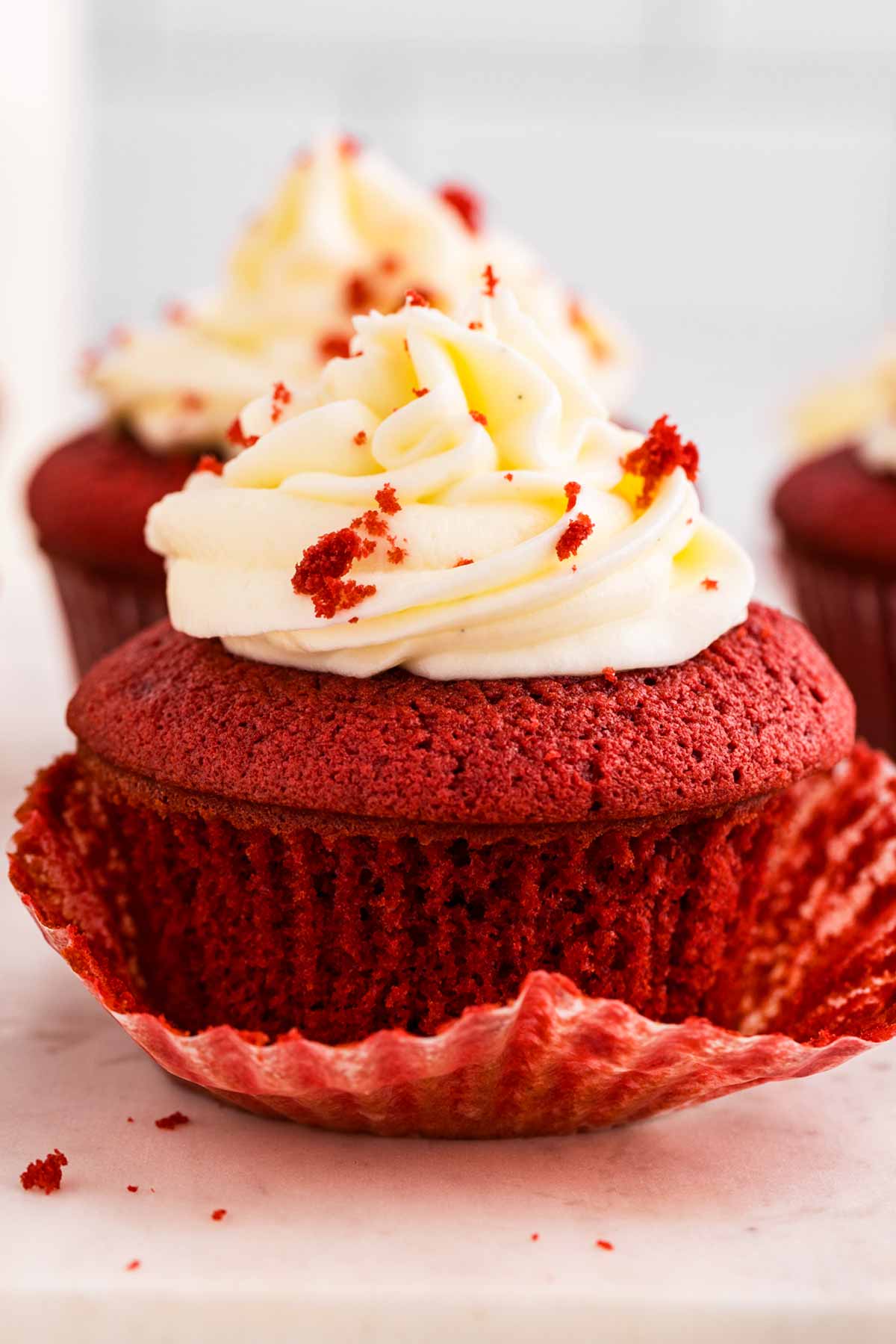 frontal view of red velvet cupcake with liner halfway removed