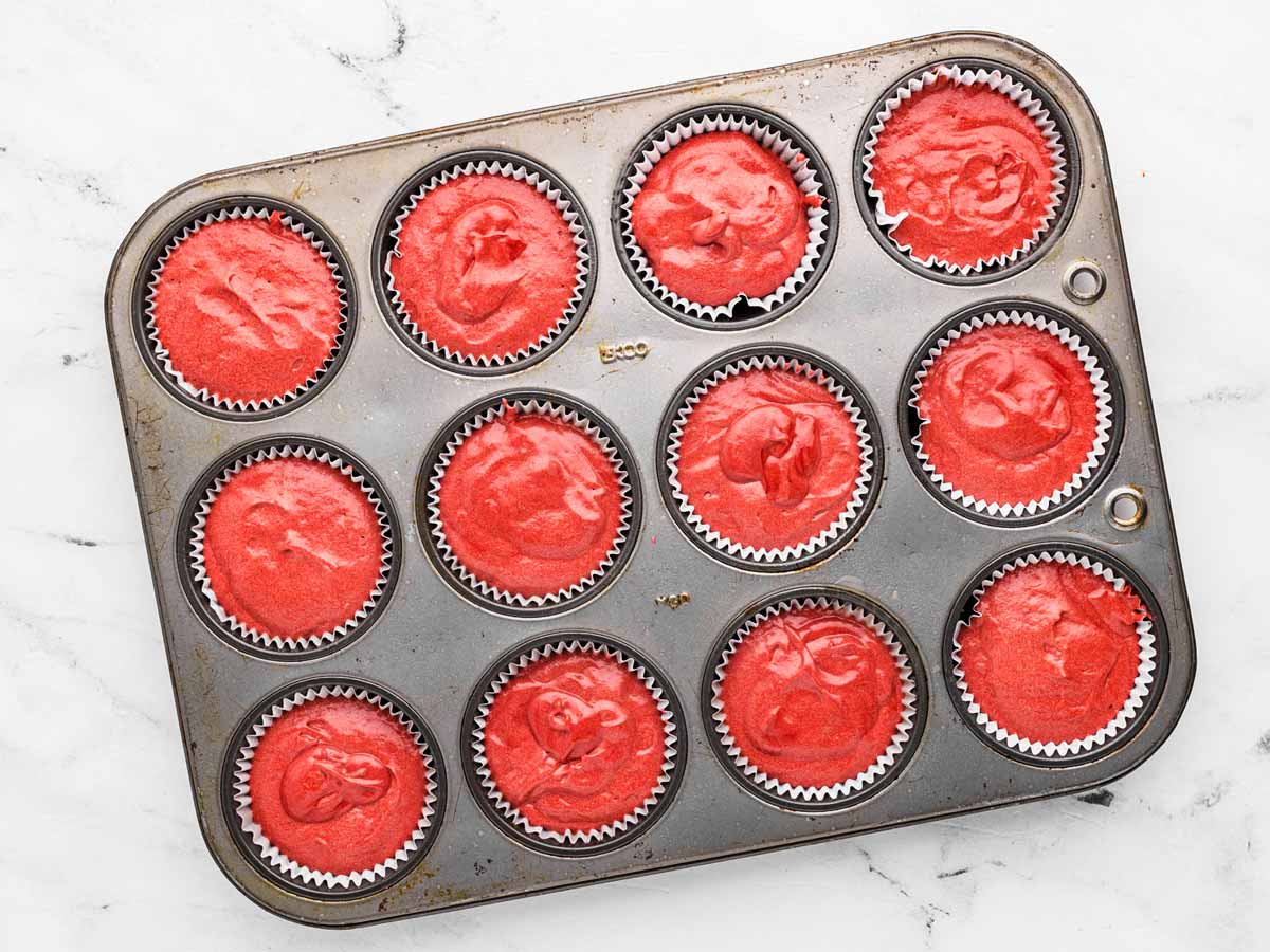 overhead view of red velvet cake batter in cupcake pan