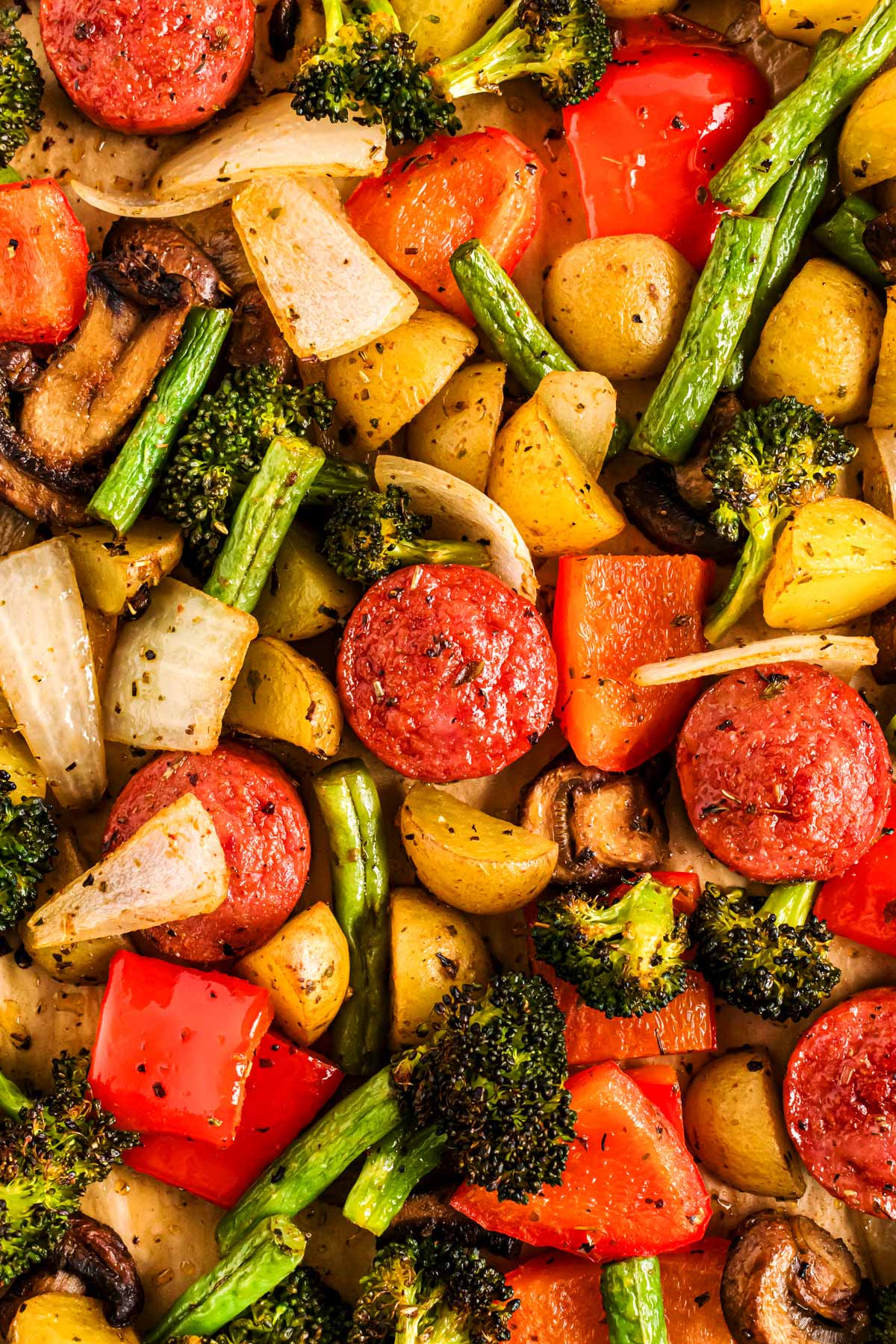 overhead close up view of sausage and vegetables roasted on a sheet pan