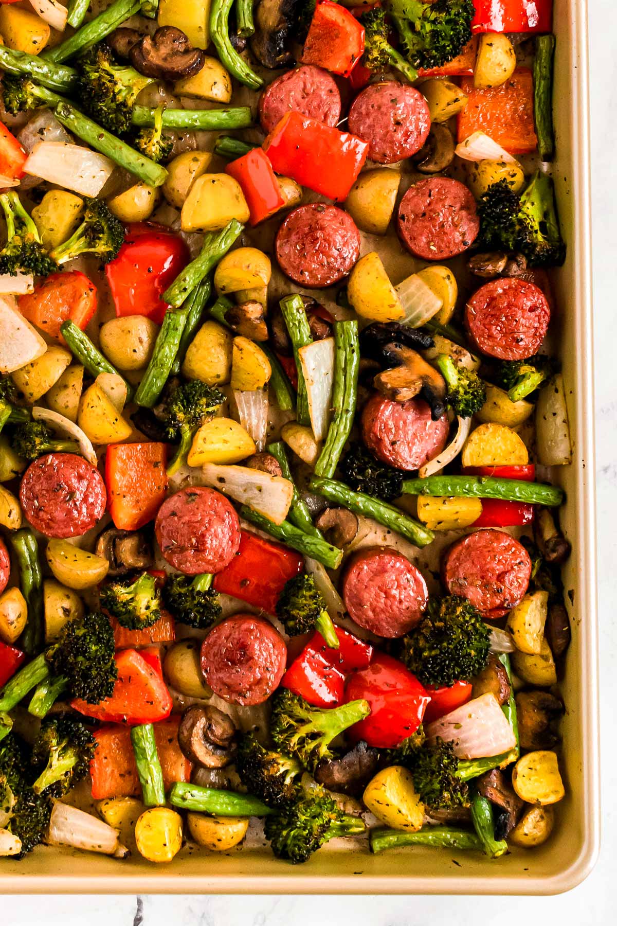 overhead close up view of sheet pan filled with roasted vegetables and sausage slices