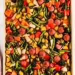 overhead view of roasted vegetables and sausage slices on sheet pan