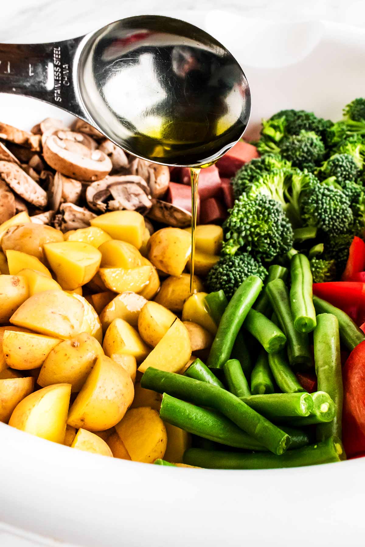 frontal view of oil drizzling over vegetables