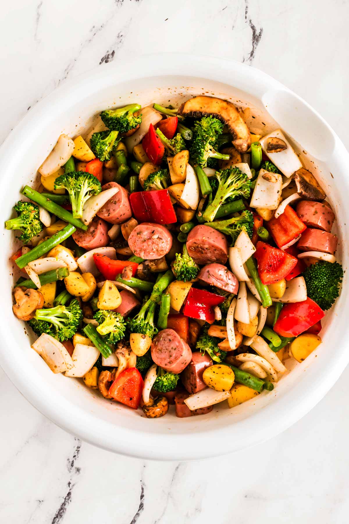 overhead view of seasoned cut up vegetables in white bowl