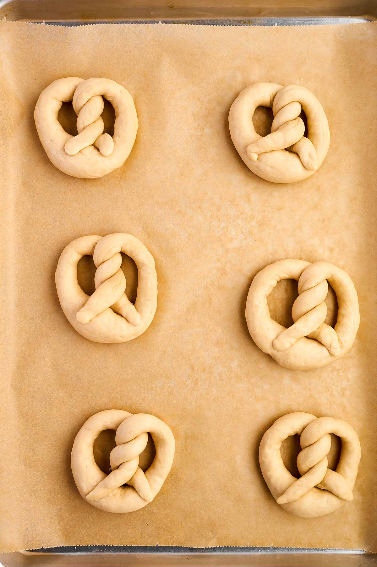 overhead of unrisen pretzels on baking sheet