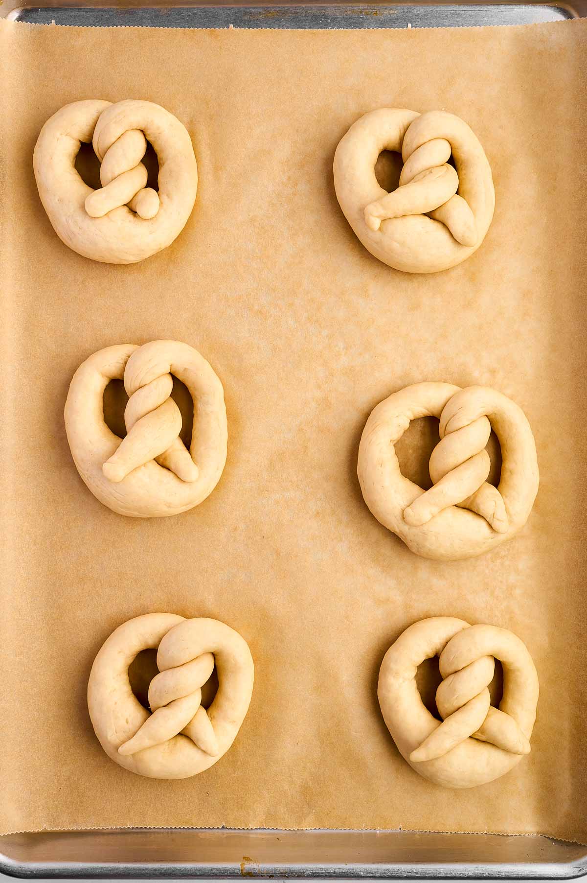 overhead of risen pretzels on baking sheet