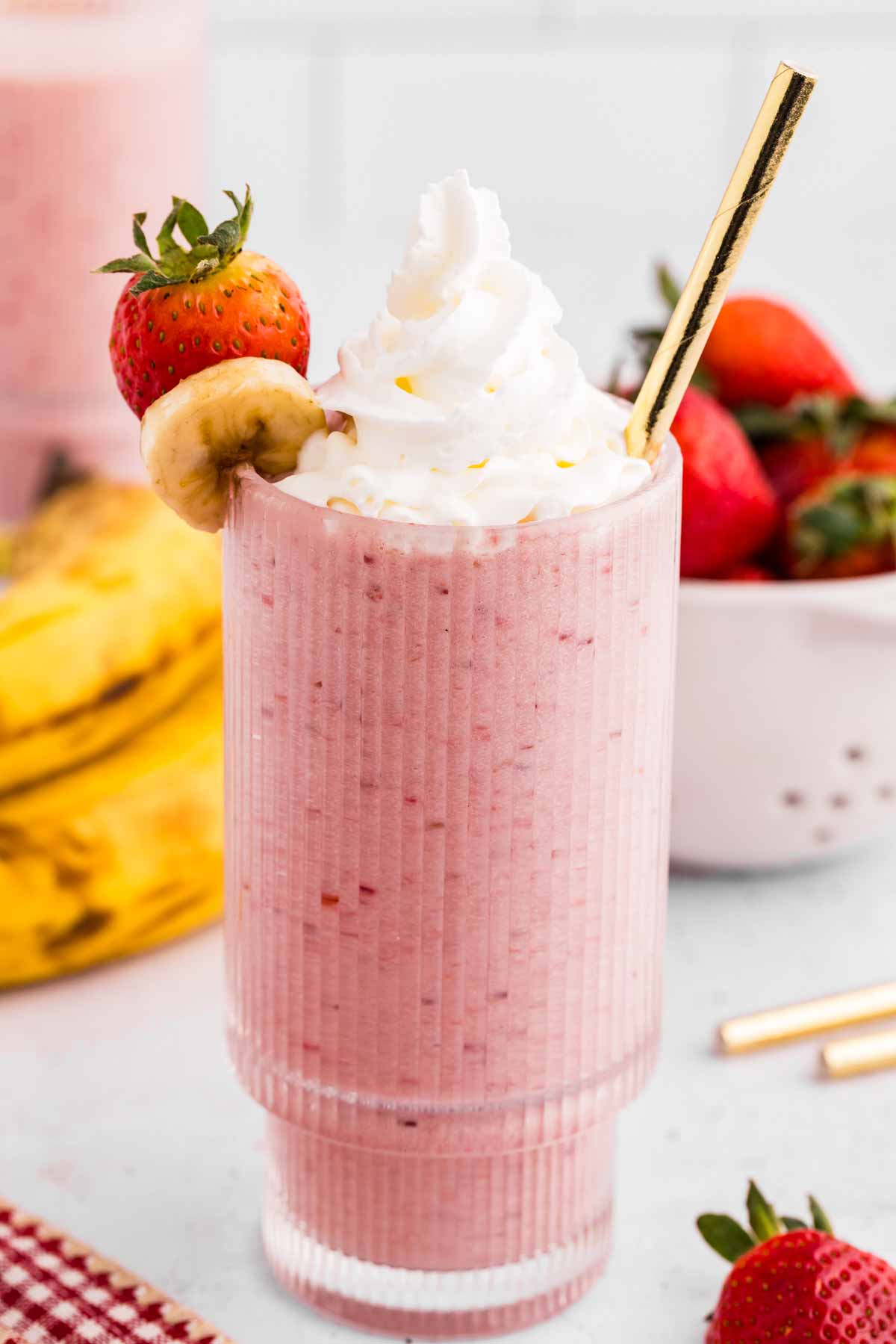 frontal view of glass filled with strawberry banana smoothie and topped with whipped cream