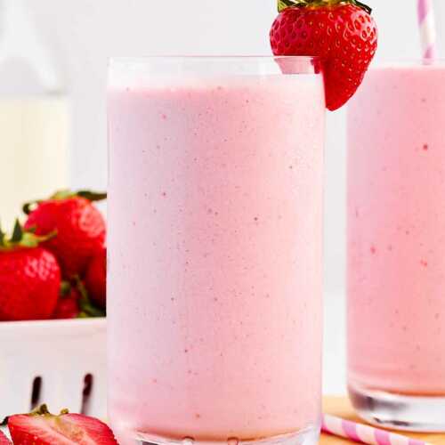 frontal view of strawberry smoothie in glass decorated with fresh strawberries