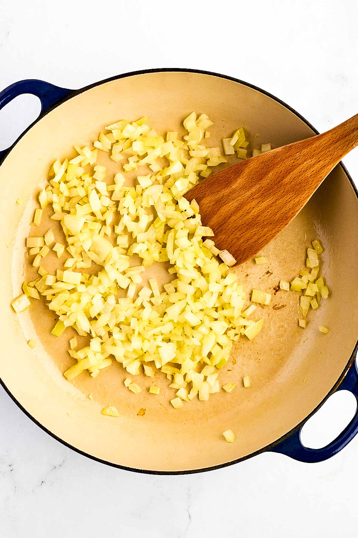 overhead view of diced onion softening in oil in dutch oven