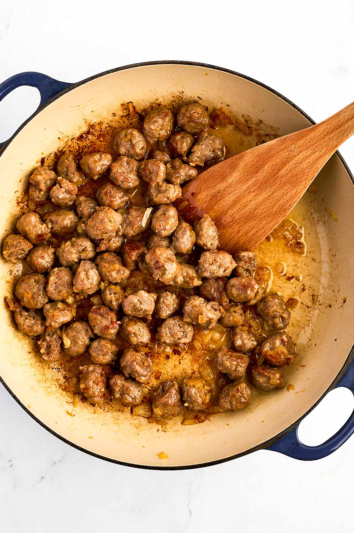 overhead view of browned sausage and softened onion in dutch oven