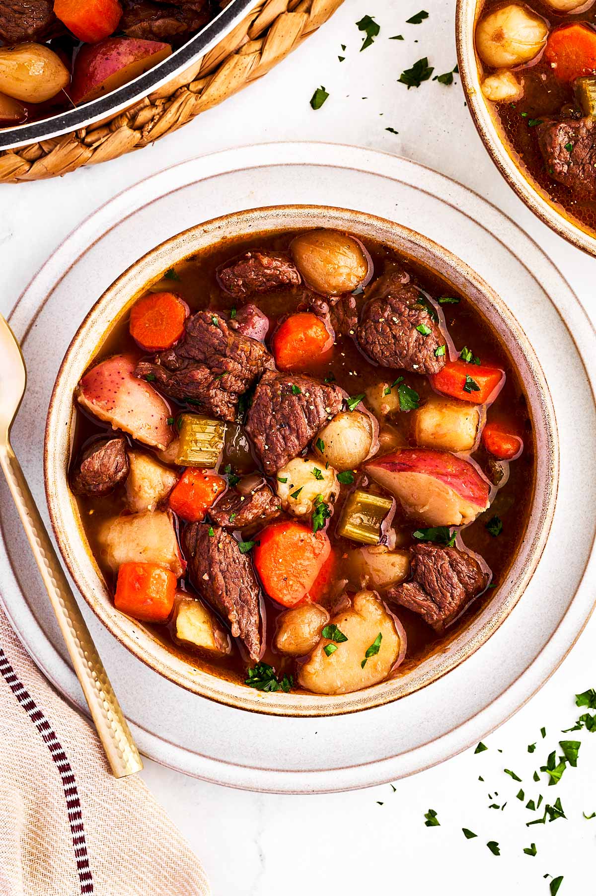 overhead view of beef stew in bowl surrounded by more bowls