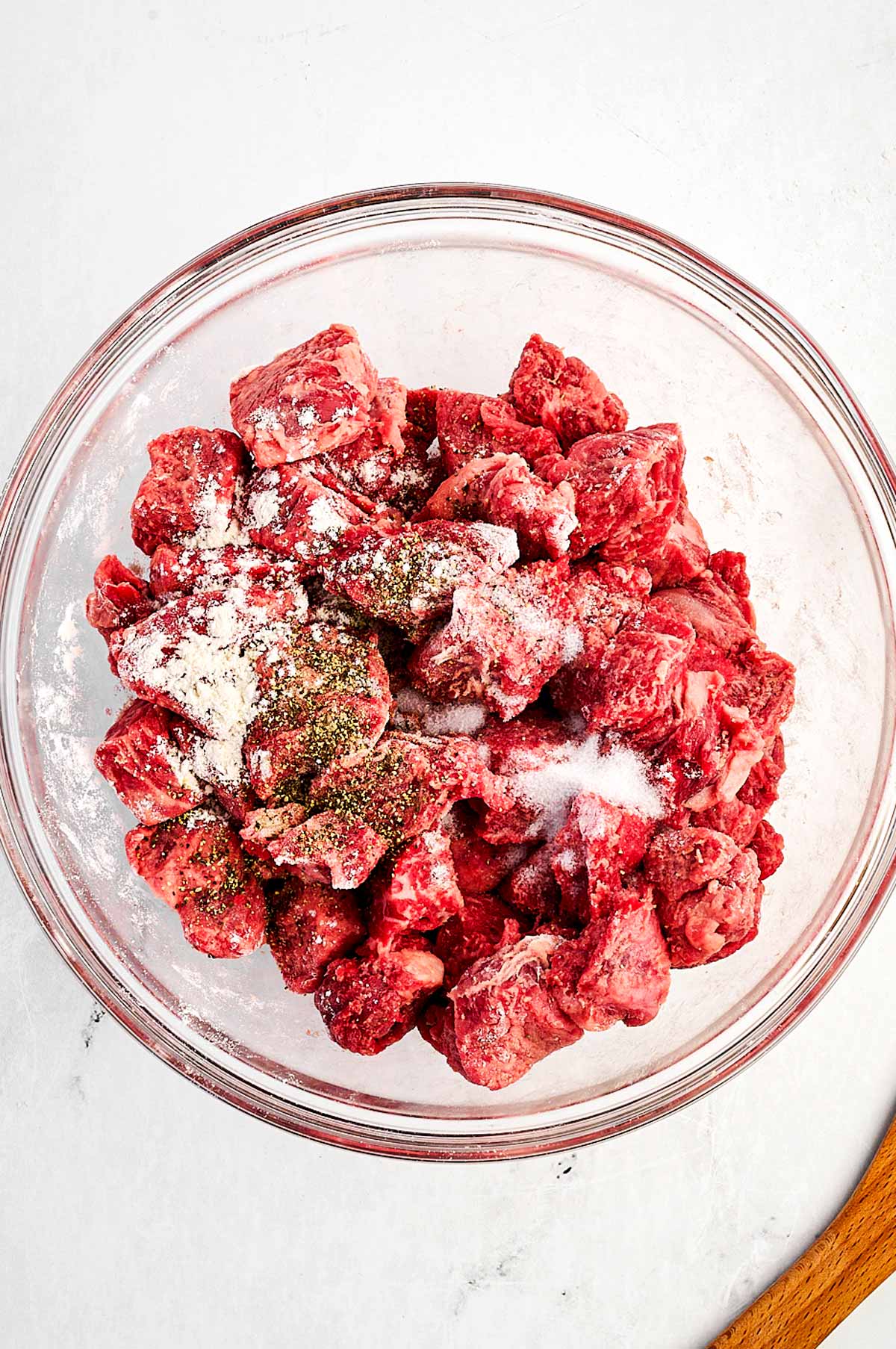 overhead view of beef cubes with flour in bowl