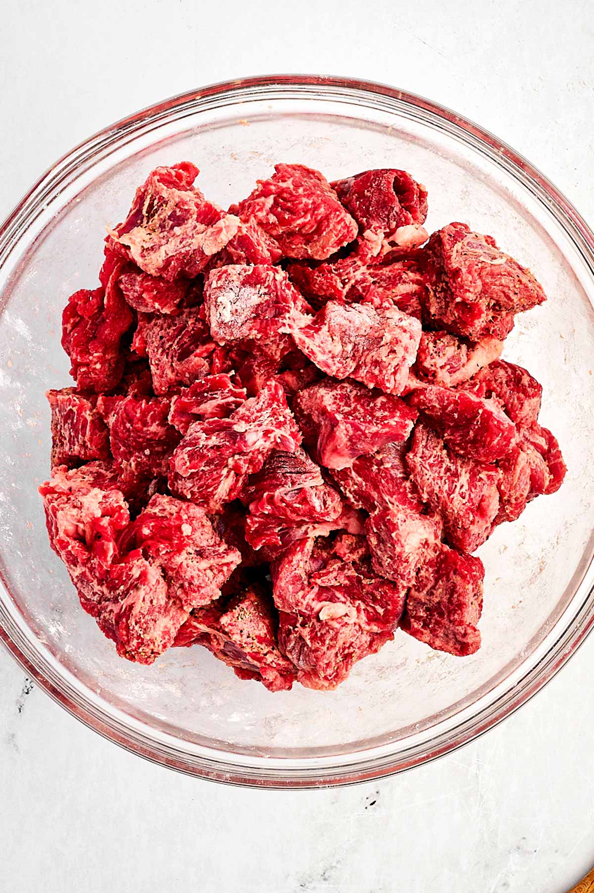 overhead view of floured beef cubes in bowl