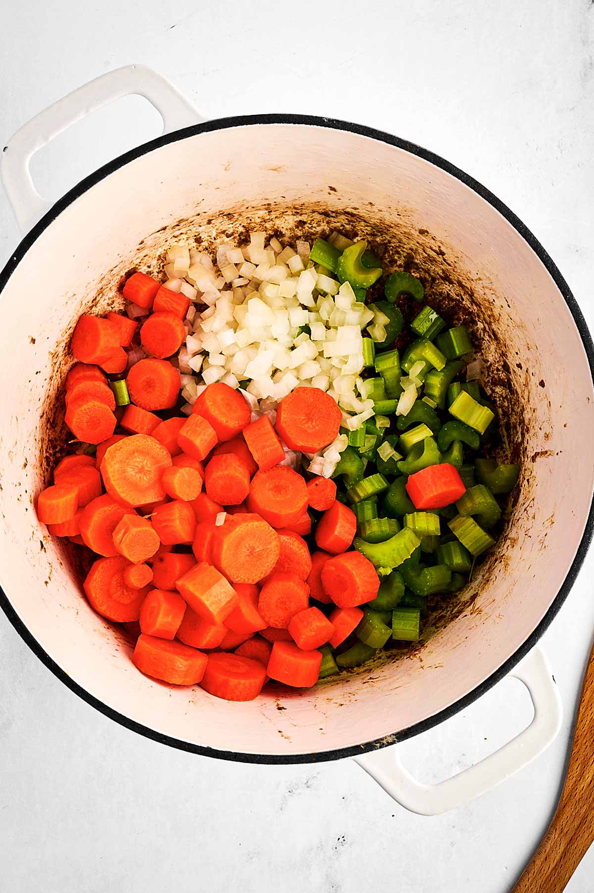 overhead view of onion, celery and carrot in Dutch oven